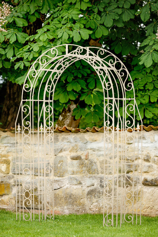 Rosenbogen Calabria in pulverbeschichtet Sonderfarbe RAL 9001 Cremeweiß in einem grünen Garten Rosenbogen Calabria in pulverbeschichtet Sonderfarbe RAL 9001 Cremeweiß in einem grünen Garten