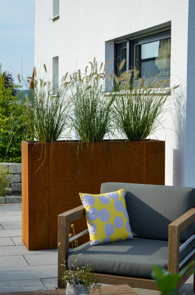 Hochbeet Manarola 40x136x100 in Cortenstahl bepflanzt auf einer Terrasse hinter einem Loung-Chair